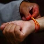 दांए हाथ में लाल धागा बांधे व्यक्ति का चित्र, भारतीय संस्कृति और धार्मिक प्रतीक दिखाते हुए